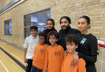 Image of the Fekiri family at the Downtown Y. Triplet boys stand in front wearing orange with older sister, father, mother and older brother in the back row.