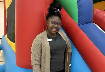 [Image] Akosua at a Y Winnipeg children's event standing in front of a bouncy castle