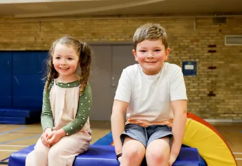 Two Kids at Obstacle Course Sitting on Large Foam Box