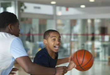 two teenagers playing basketball in a gymnasium setting