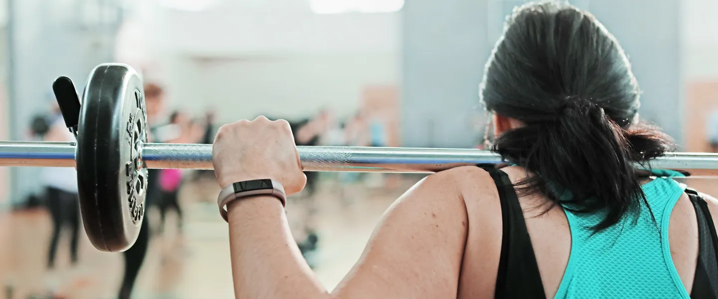 Back View of Woman Lifting Weights in a Class