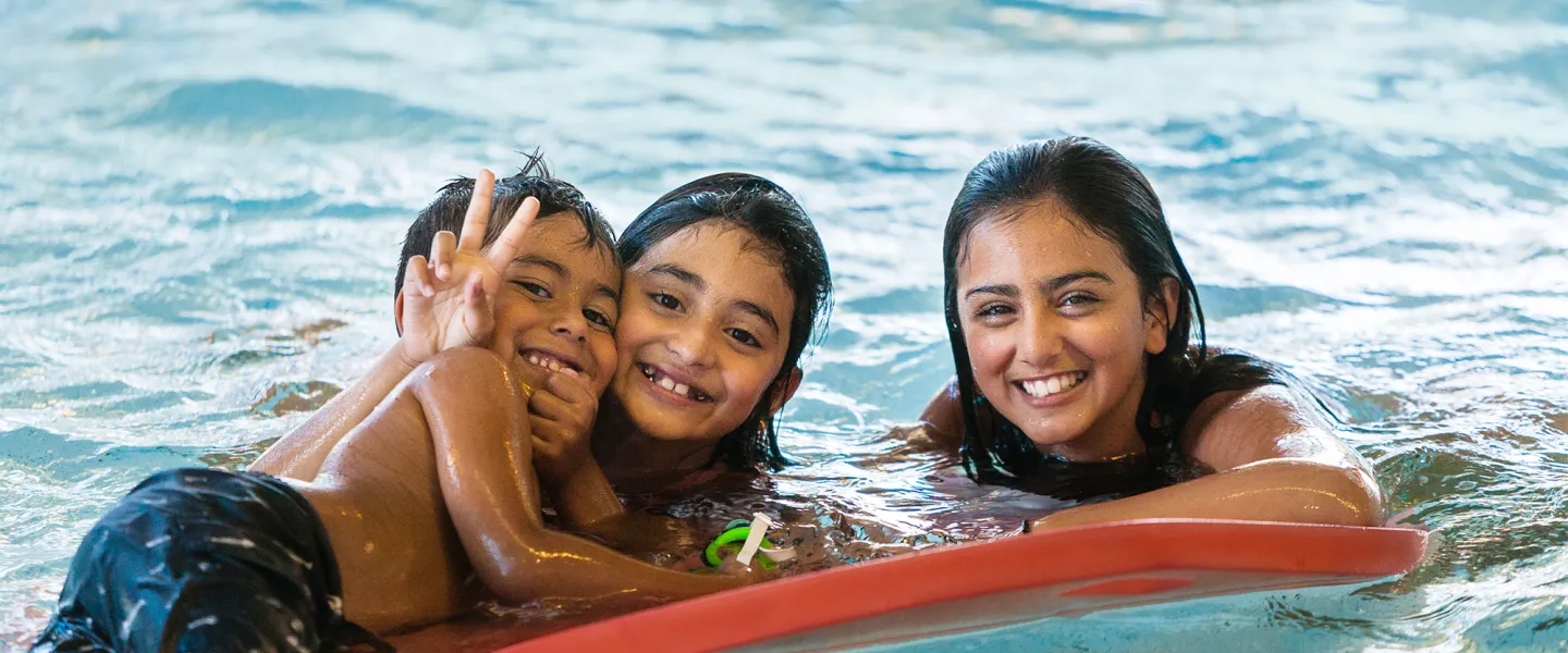 Three Kids Playing with a Flutter Board in the Pool