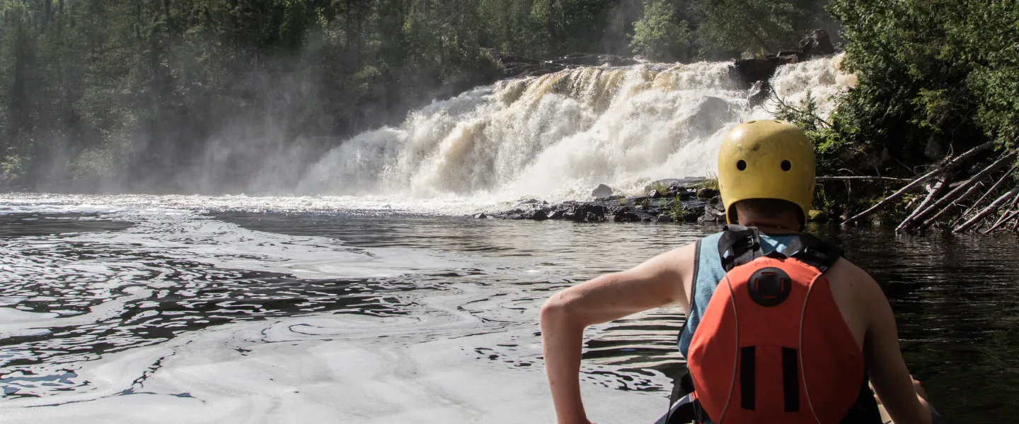 canoeist looking at waterfall scenery