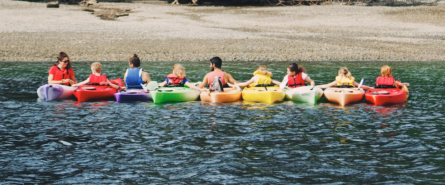 large group of people in a row of kayaks on the water