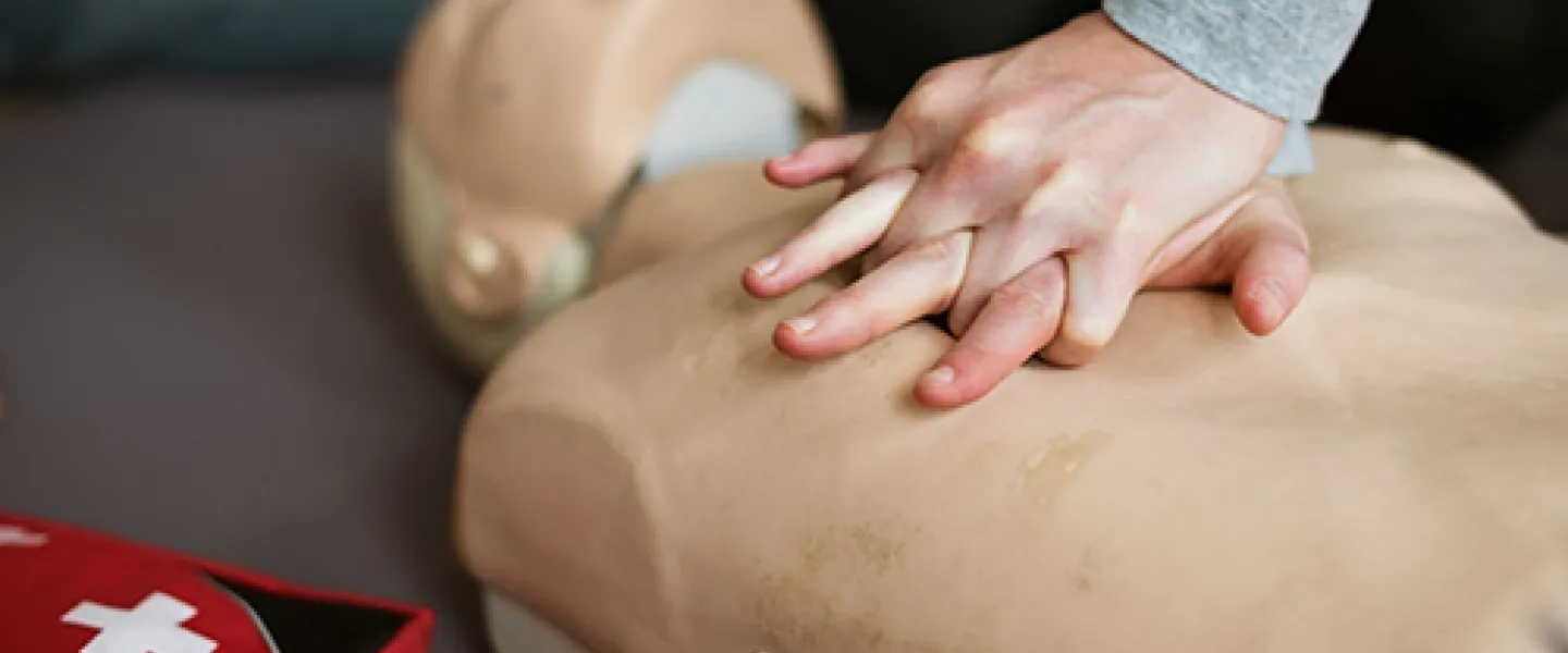 [Image] close-up of person performing chest compressions on CPR dummy