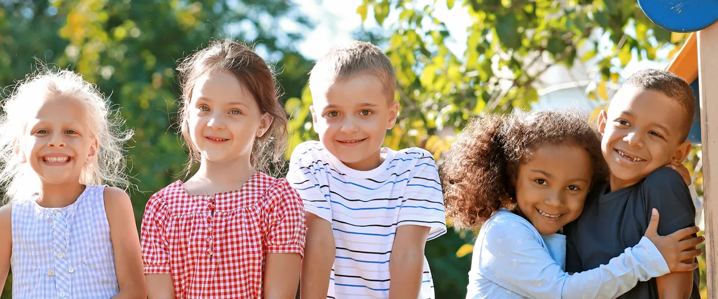 diverse group of children smiling while outside on sunny day