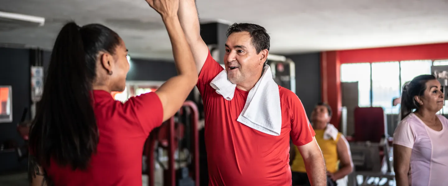 [Image] Man in fitness centre giving coach a high five