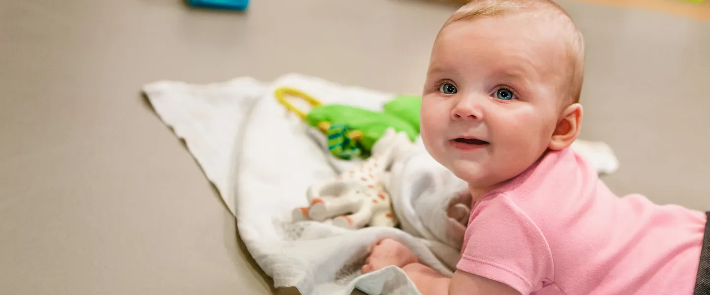 infant doing tummy-time on blanket with toys