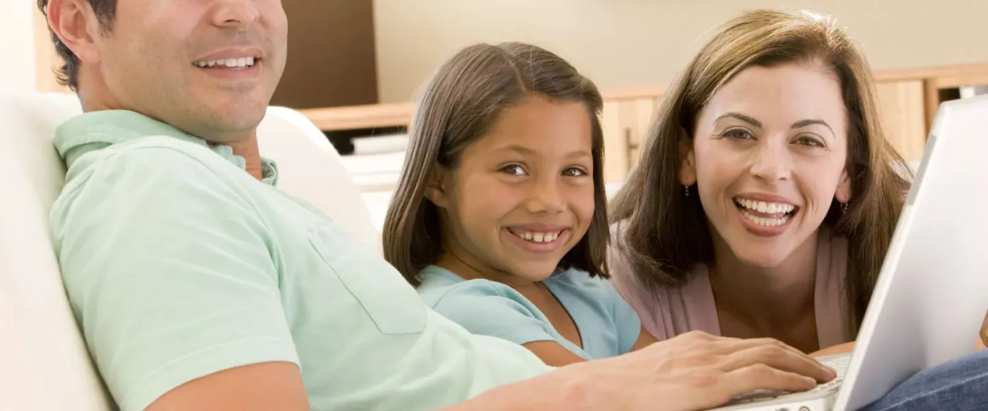 image of family sitting on the couch with a laptop