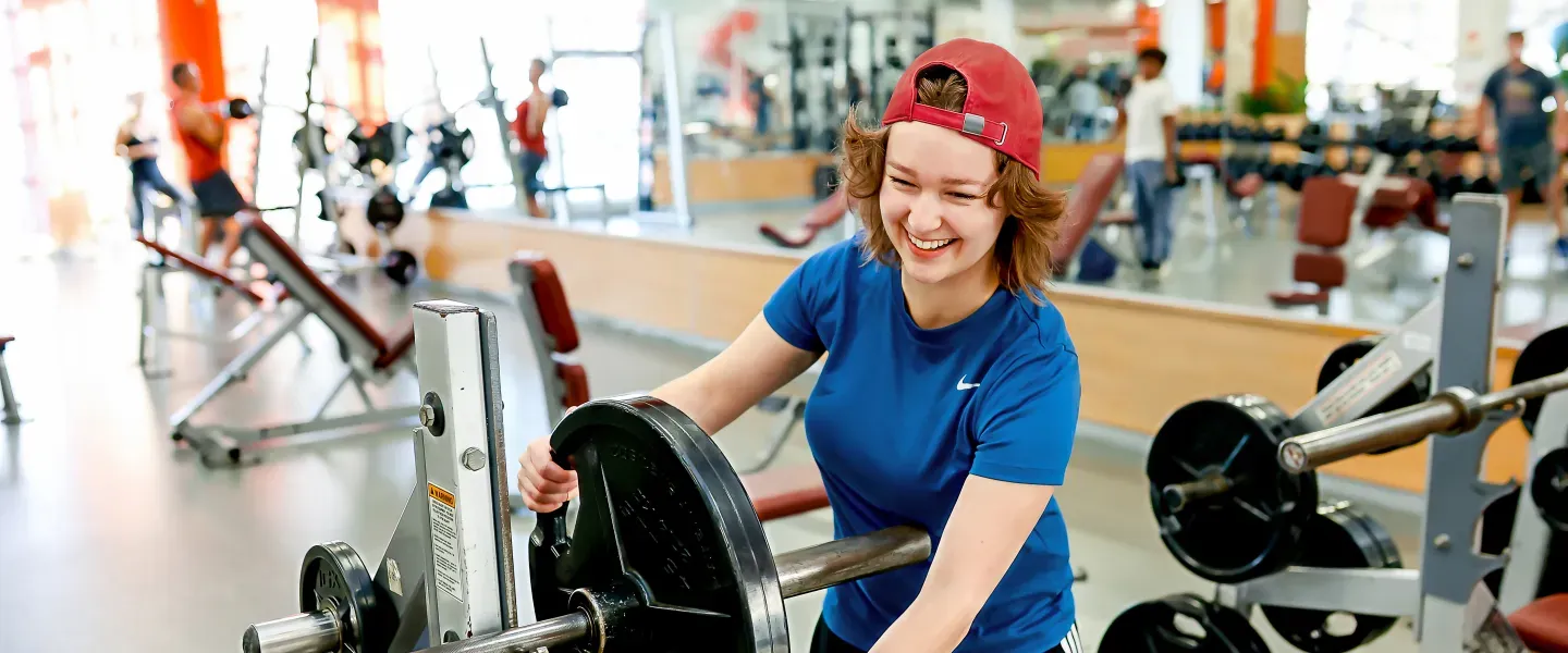 Image of girl wearing a reversed red baseball cap adding weights