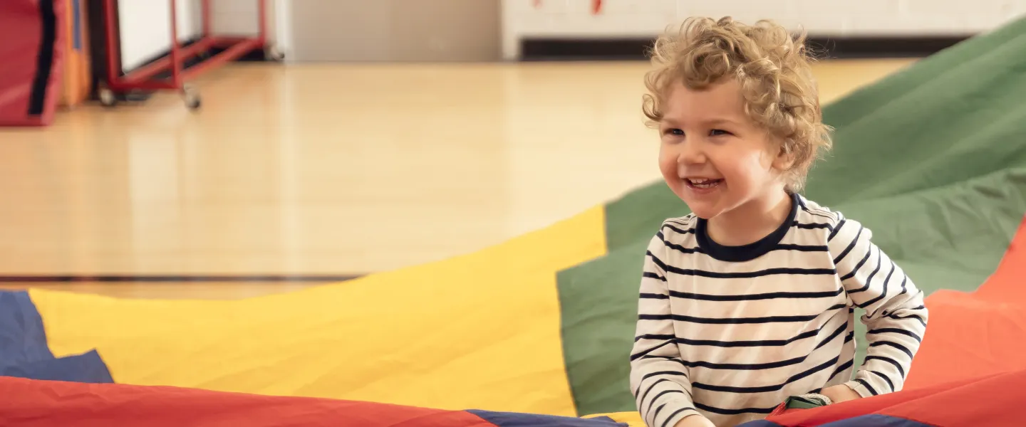 Preschool kid playing with parachute