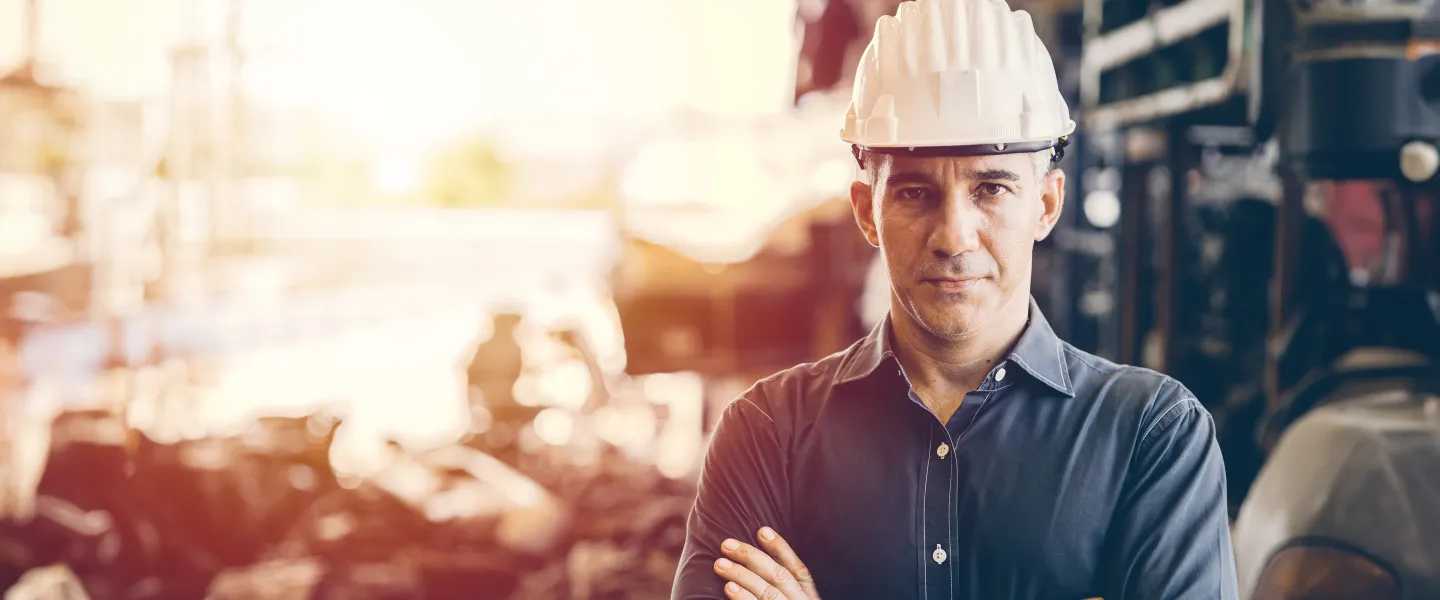 [Image} man with hard hat standing in front of construction site