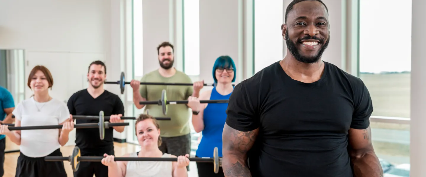 group of people lifting barbells in a fitness class