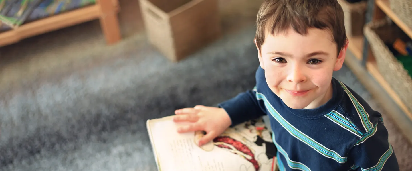 [Image] school aged boy sitting and reading a story