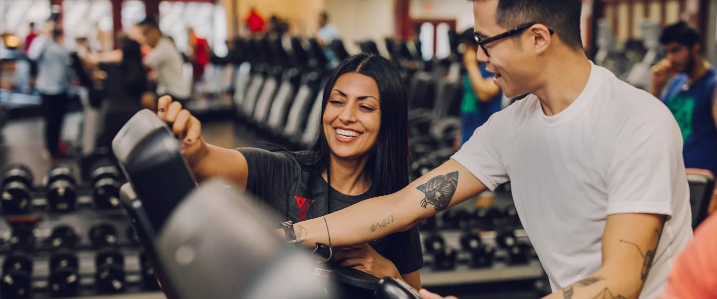 Staff showing member how to work cardio machine