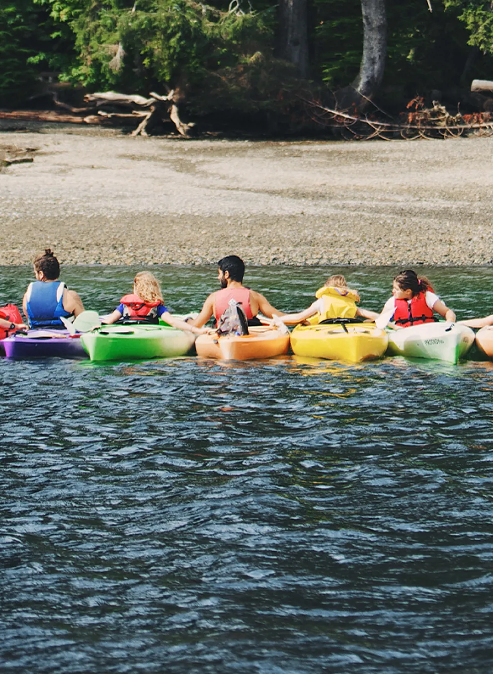 large group of people in a row of kayaks on the water