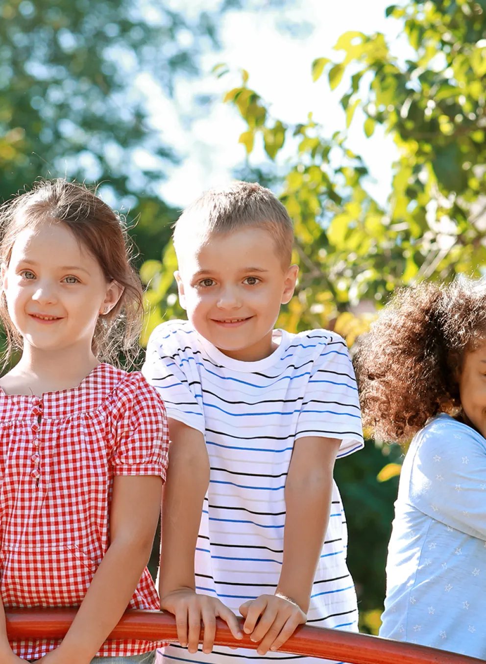 diverse group of children smiling while outside on sunny day