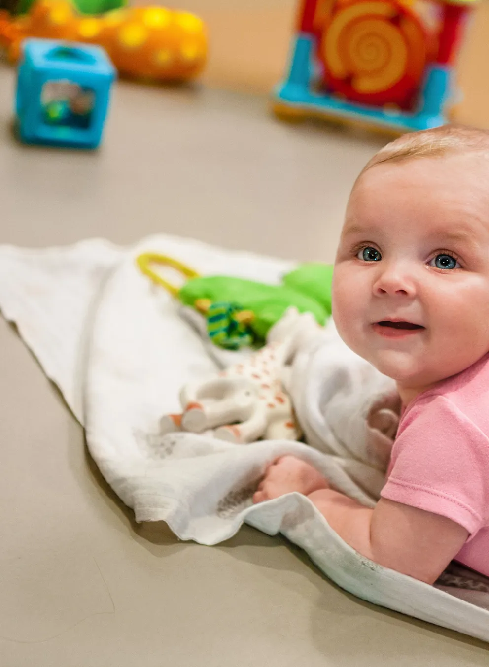 infant doing tummy-time on blanket with toys