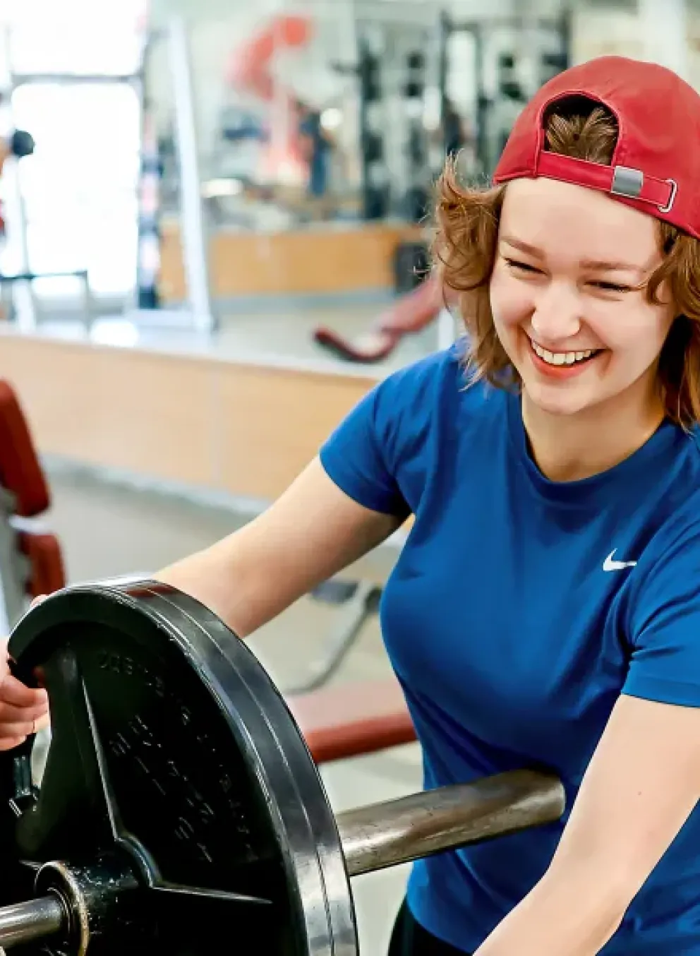 Image of girl wearing a reversed red baseball cap adding weights