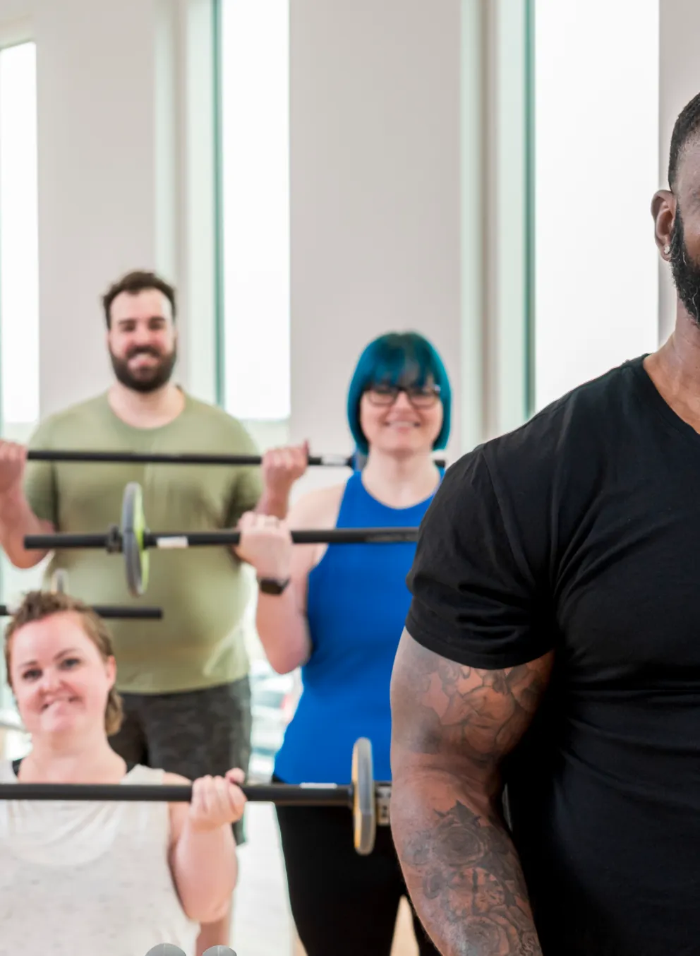 group of people lifting barbells in a fitness class