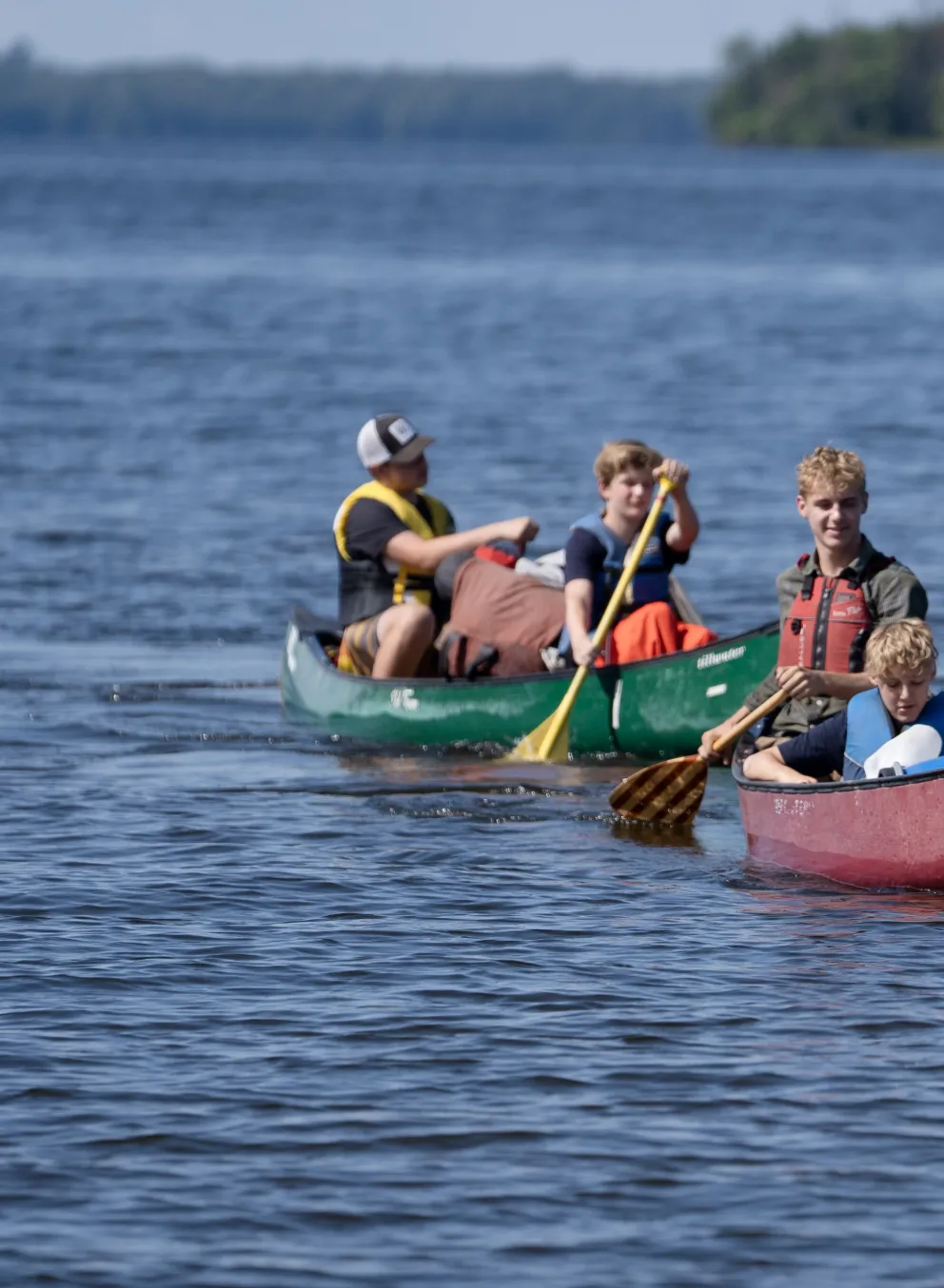 two canoes with boys paddling on the lake