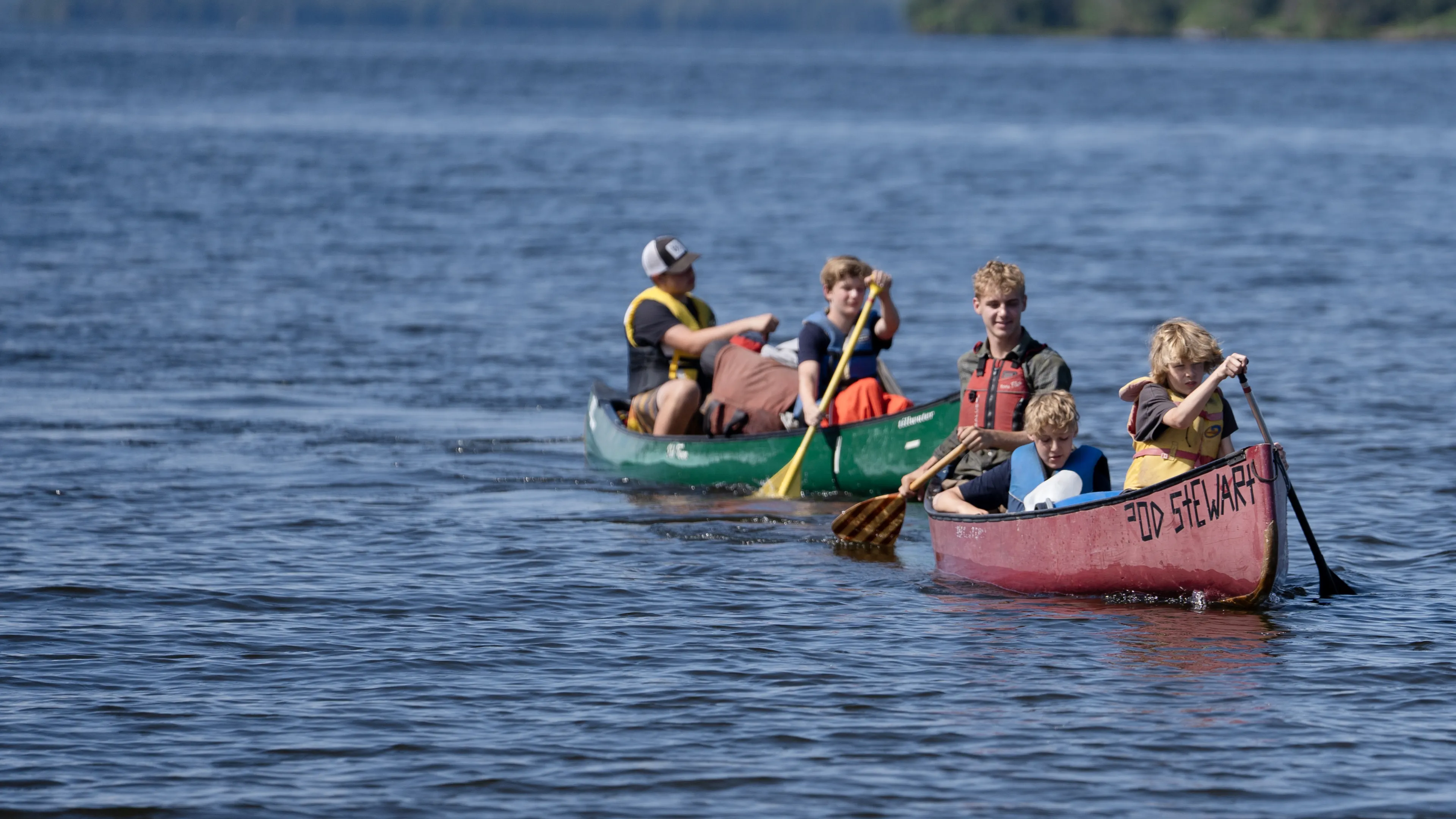 two canoes with boys paddling on the lake