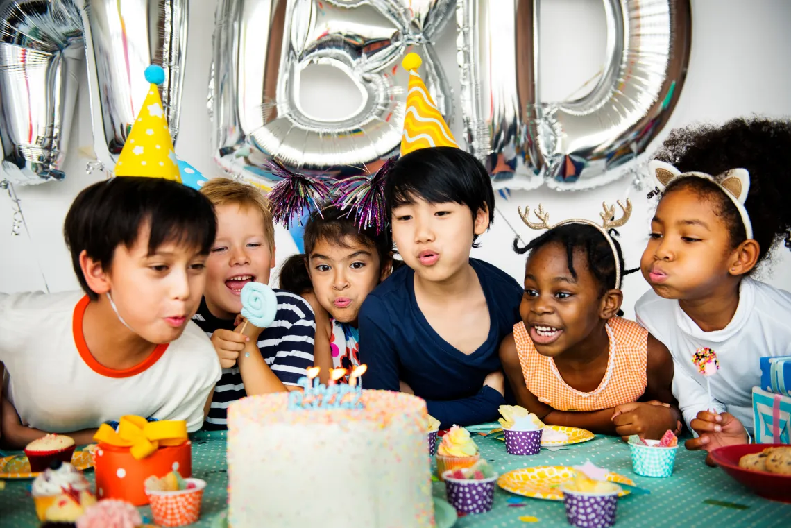 Kids blowing out candles on a birthday cake