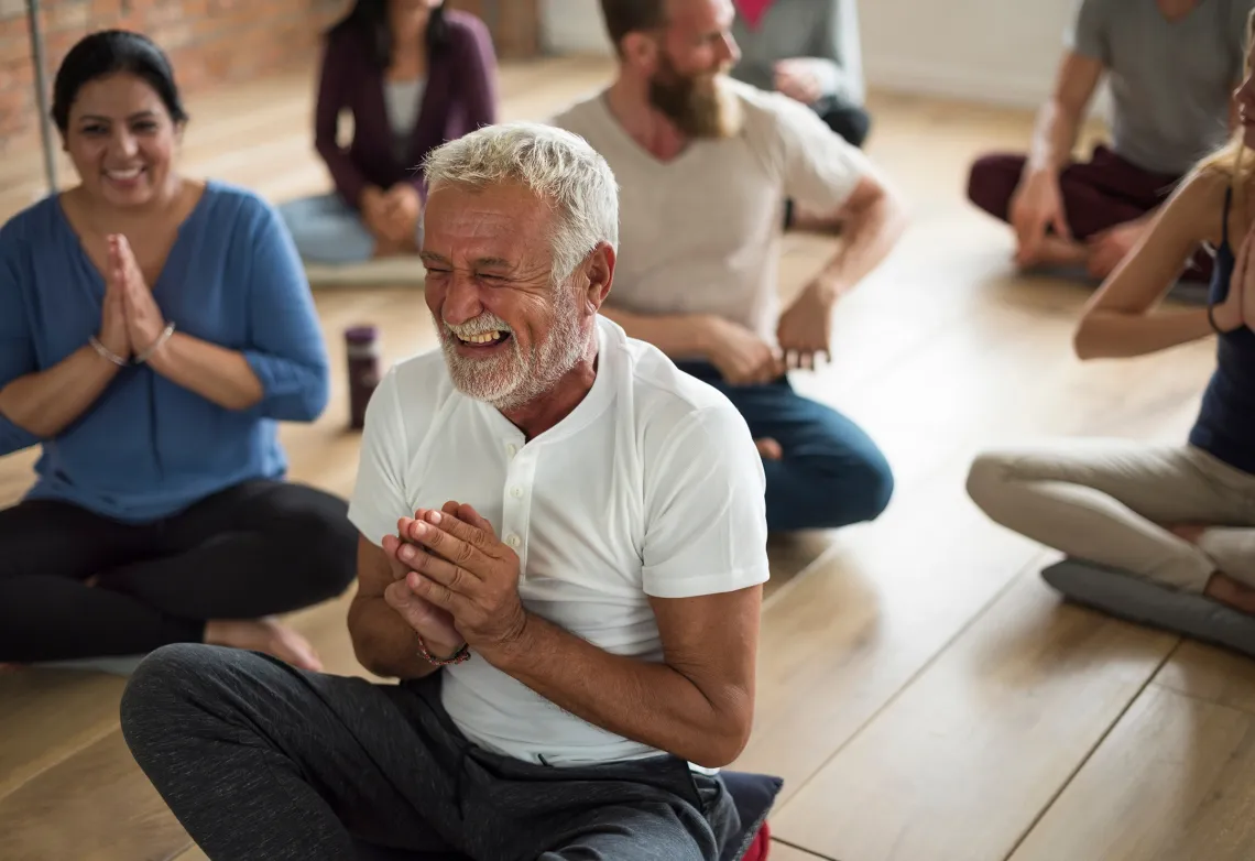 Smiling man in sitting cross-legged with hands in prayer position