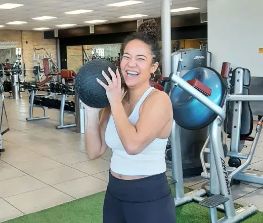 smiling woman in gym with a medicine ball