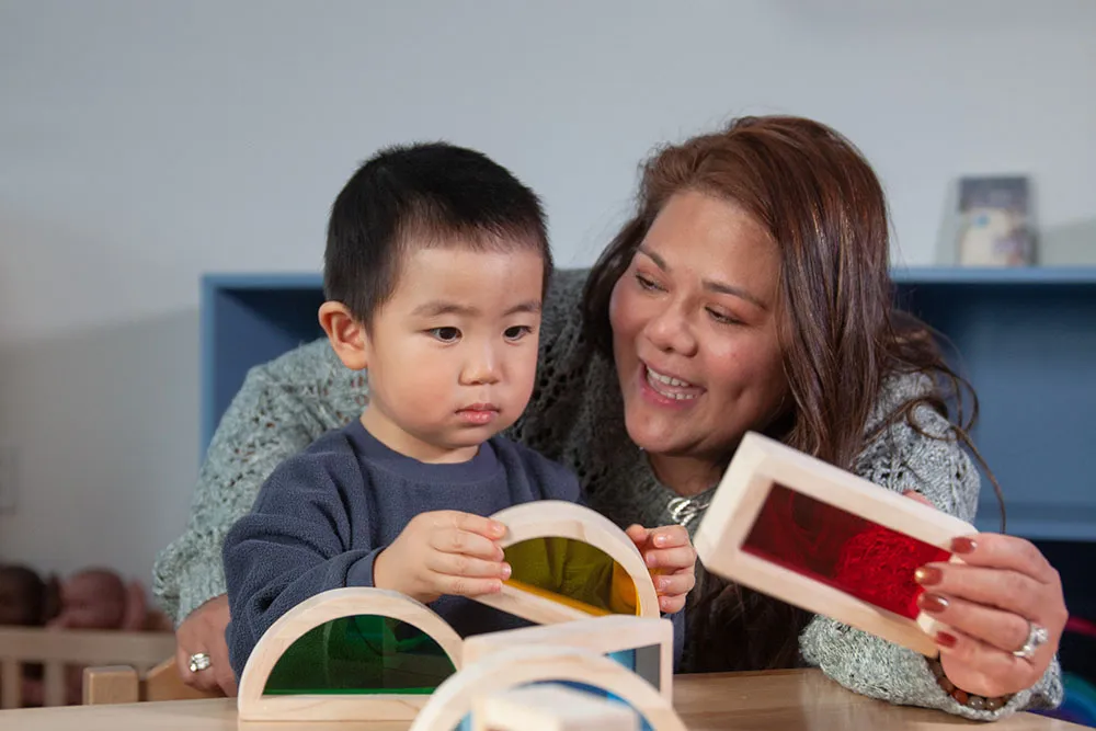 Image of woman teaching young asian boy with coloured wooden blocks