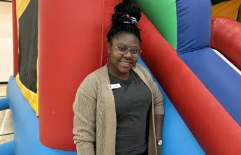 [Image] Akosua at a Y Winnipeg children's event standing in front of a bouncy castle