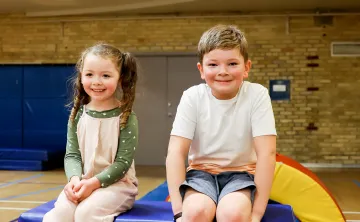 Two Kids at Obstacle Course Sitting on Large Foam Box