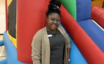 [Image] Akosua at a Y Winnipeg children's event standing in front of a bouncy castle