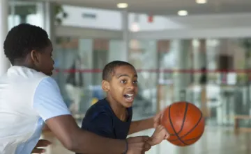 two teenagers playing basketball in a gymnasium setting