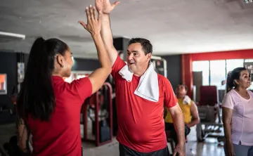 (image) male high-fiving another member inside a fitness facility